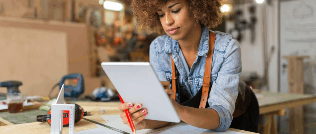 A imagem mostra uma pessoa empreendedora em seu local de trabalho. Ela está com um tablet nas mãos, representando um profissional que está se informando sobre as novas regras do Simples Nacional para quem é MEI.
