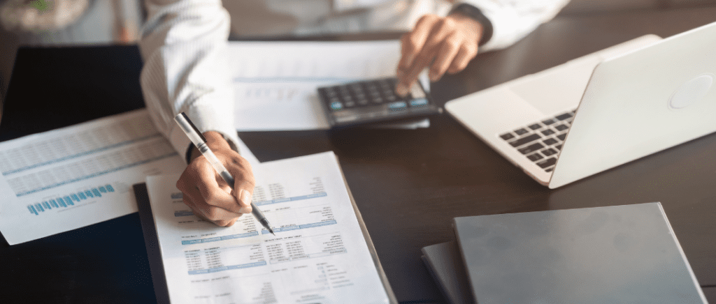 A imagem mostra uma pessoa fazendo cálculos em uma mesa, representando um empresário que está analisando e se adaptando às novas tributações e mudanças no Imposto de Renda por causa da Lei 15.270/2025.