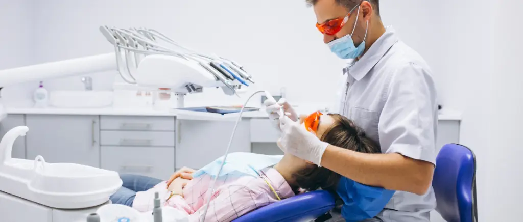 A imagem mostra um dentista em seu consultório atendendo um paciente, representando a profissão que precisa entender a nova lei para saber se deve atuar como PF ou PJ.